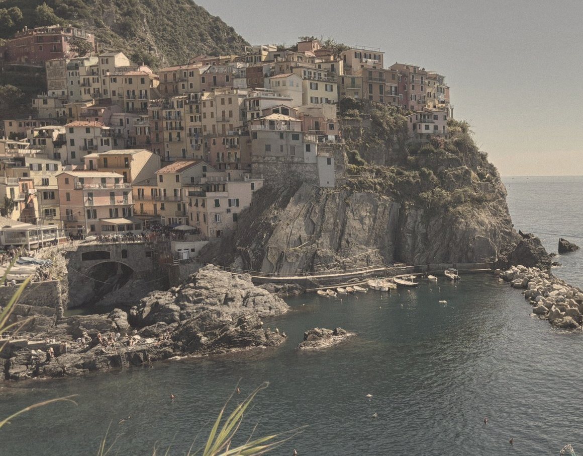 A cliffside village of pastel houses above a quiet harbour